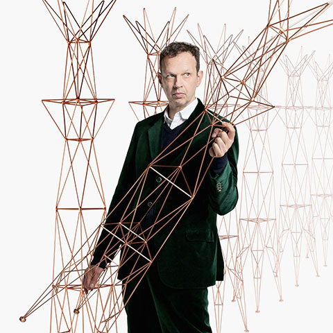 designer tom dixon holding wire sculptures
