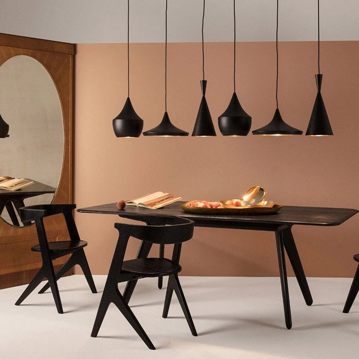 tom dixon beat pendant light above a black table and chairs