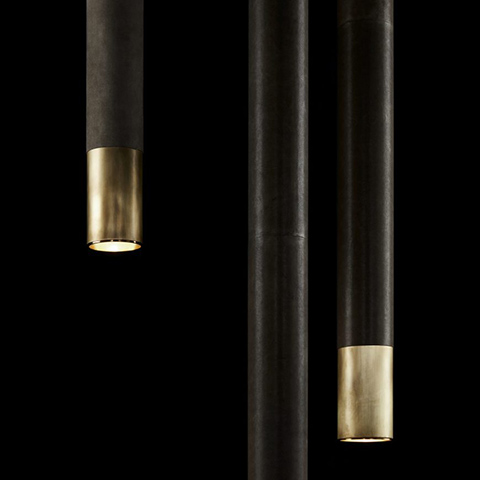 close up of three apparatus cylinder pendants in aged brass finish with leather wrap